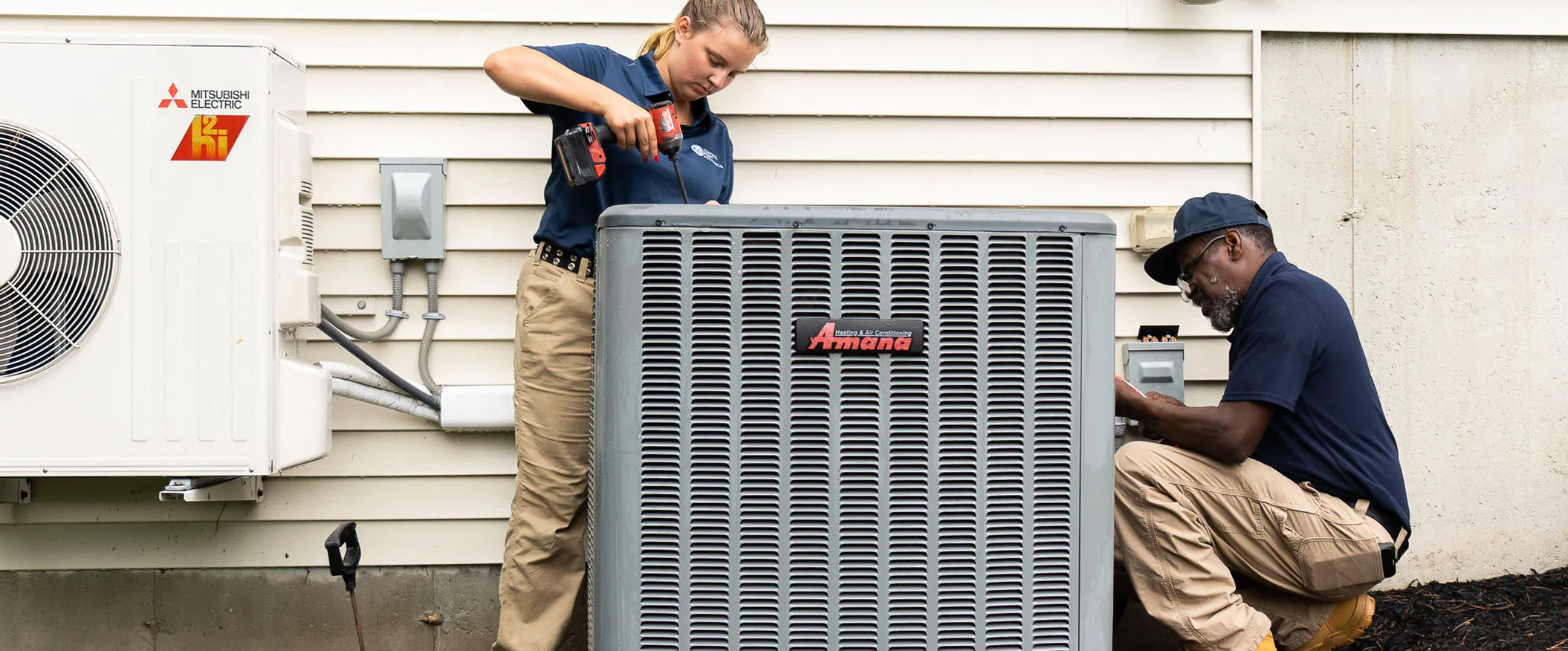 Two Daikin outdoor air conditioning units installed on a concrete pad next to a building with electrical connections.