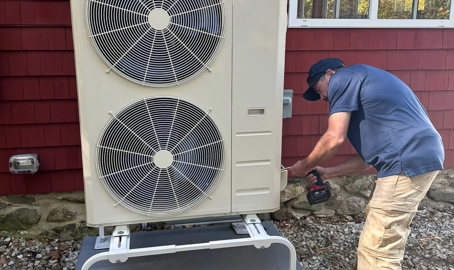 Technician adjusting a ceiling-mounted air conditioning unit in a well-lit interior space.